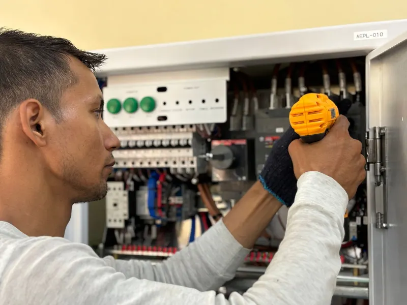 An electrician working on an electrical panel