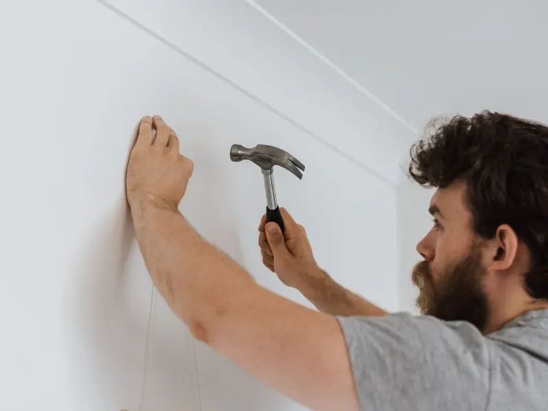 A man hammering a nail into a wall