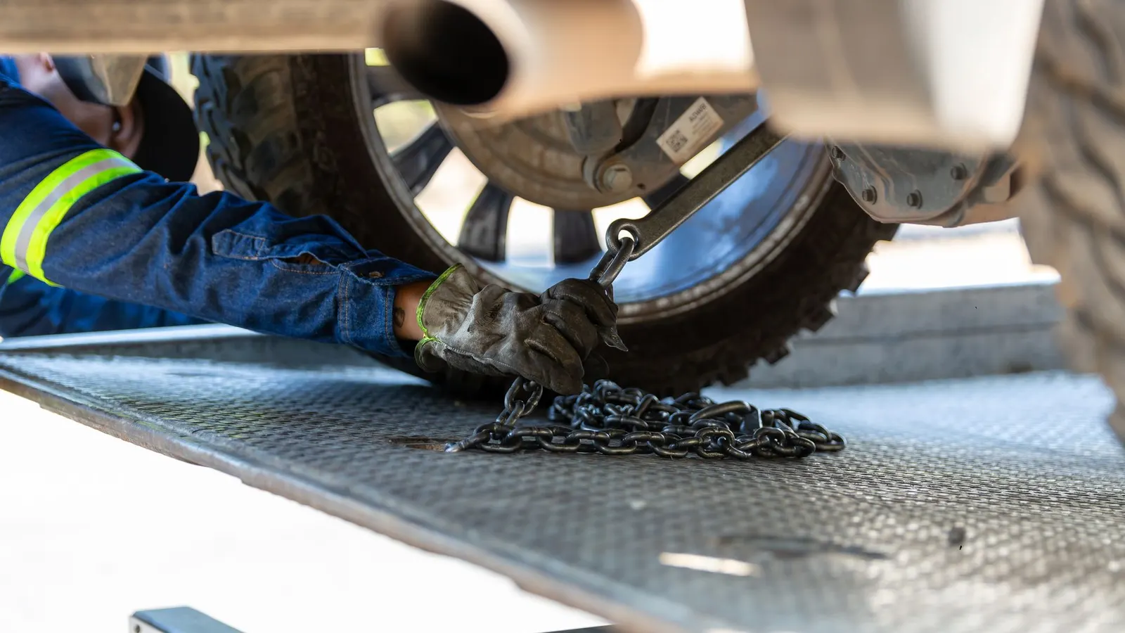 A tow operator chaining a vehicle down on a flatbed