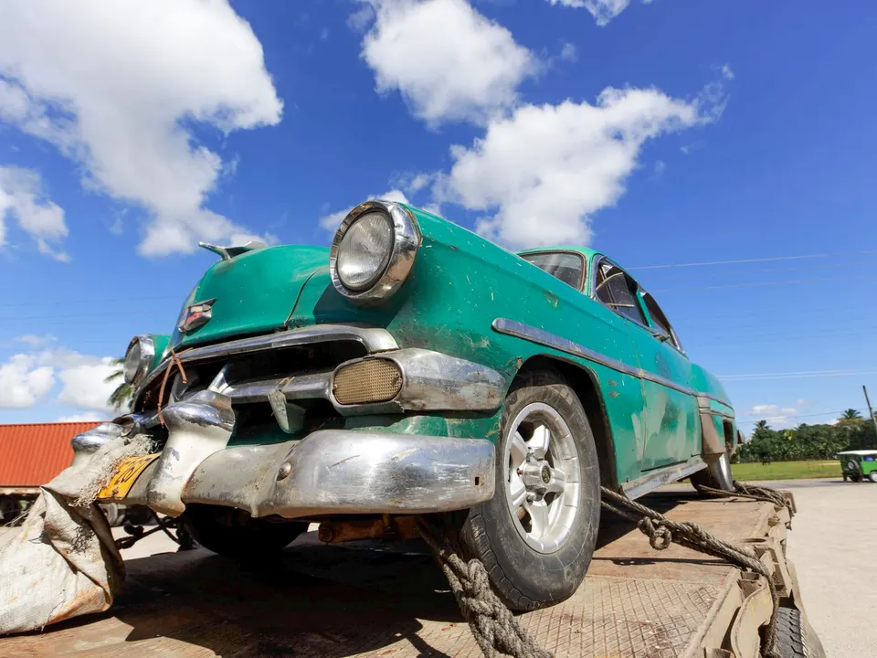 A classic car roped down on the bed of a truck