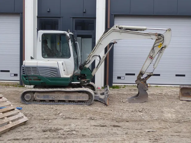 A compact excavator parked on a dirt lot